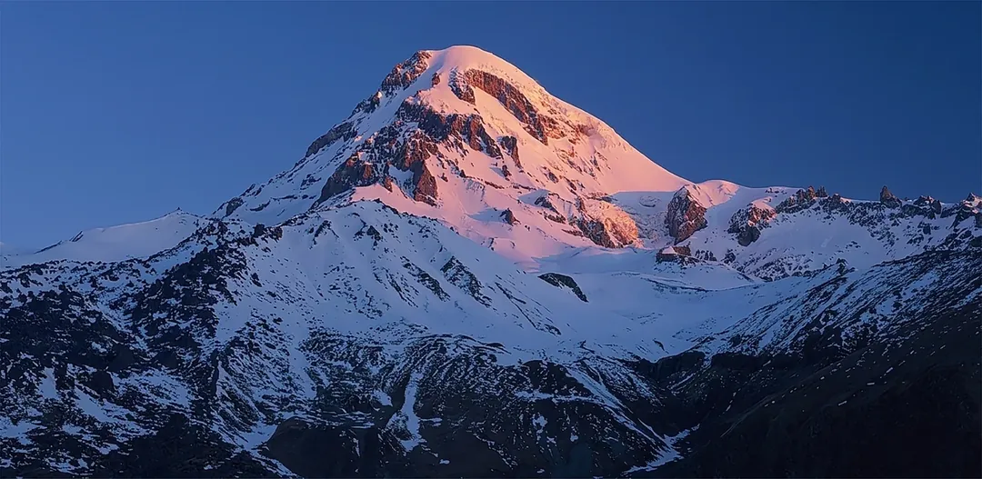 Mount Kazbek at sunrise, three ridges in front of the summit